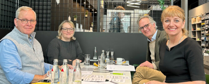 Zwei Vertreter der Alternus Organisationsberatung, Constanze Steinbüchel und Christoph von Forstner in einem modernen Café mit Schreibutensilien.